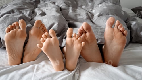 Preview: Happy family's feet lying together under the blanket. Feeling of warmth, security, and love.