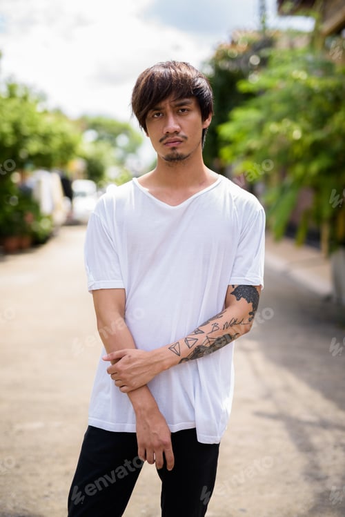 Preview: Young Asian man with hand tattoos in the streets outdoors