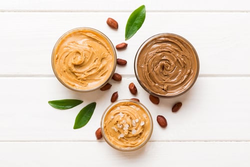 Preview: Glass jar with peanut butter on table background, top view space for text and close up