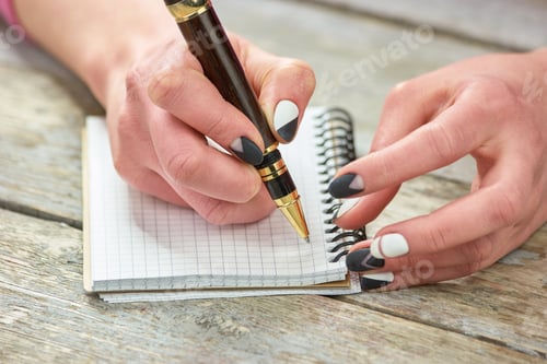 Preview: Woman with manicured hand writing on notebook