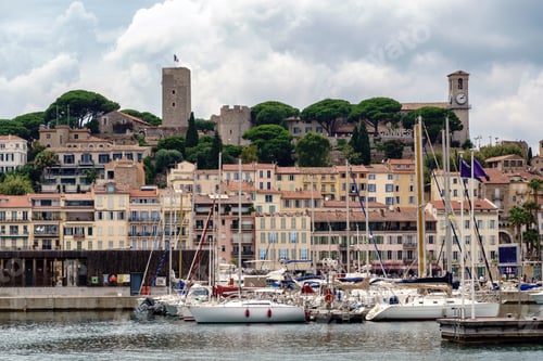 Preview: Buildings and castle tower with clock in Cannes, France, boats at the port