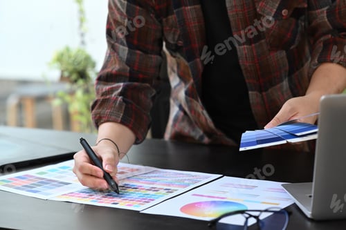 Preview: Creative designer holding working with color palette at office desk.