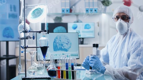 Preview: Portrait of chemist researcher with ppe equipment looking into camera while working at microbiology