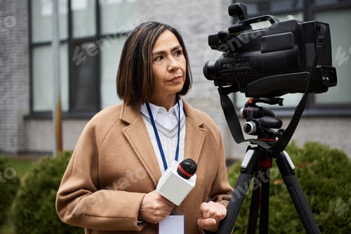 Preview: Multiracial journalist interviews on location, showcasing her professionalism in a beige coat