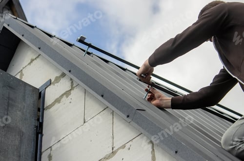 Preview: A man is installing solar panel mounts on the roof. Selective focus