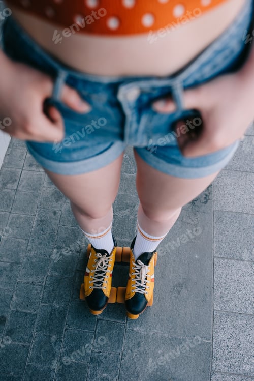 Preview: cropped shot of girl in denim shorts and roller skates standing on street
