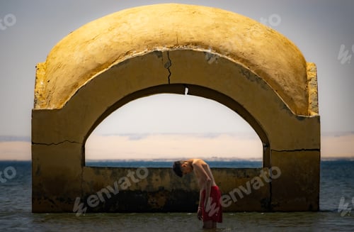 Preview: Man standing in water by the ocean and a building