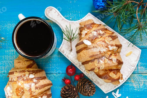 Preview: Croissants with almond flakes, coffee mug on a blue wooden background.