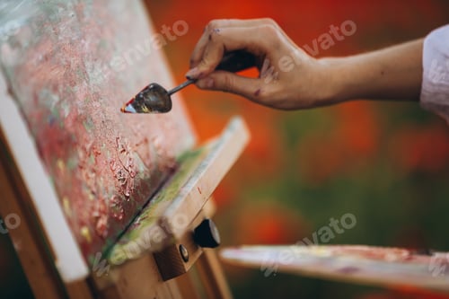 Preview: Painter using spatula while painting in poppy field