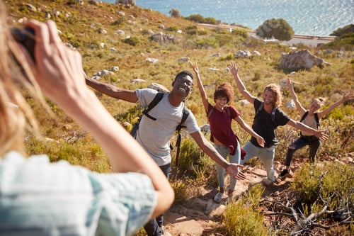 Preview: Young adult friends posing and taking photos of each other during a hike uphill on a coastal path