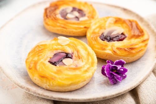 Preview: Small cheesecakes with jam and almonds with cup of coffee on a white concrete background