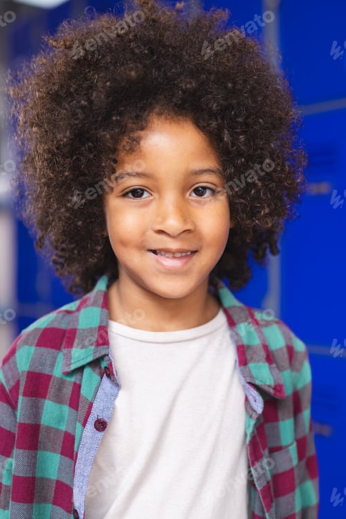 Preview: In school, young biracial boy is standing, smiling