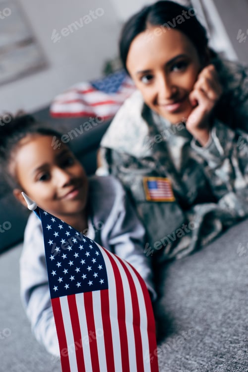 Preview: african american daughter and mother in military uniform with american flag at home