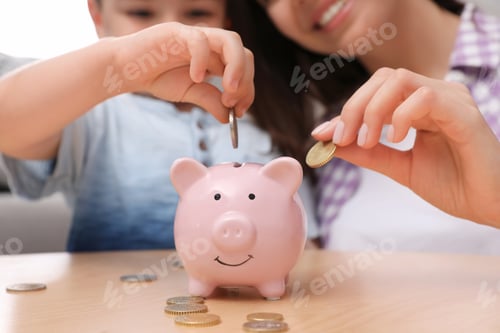 Preview: Happy mother and son putting coins into piggy bank at home, focus on hands