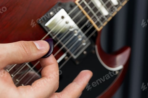 Preview: A stylish young guy plays the guitar on a dark background