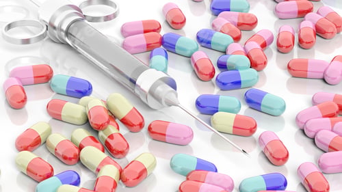 Preview: Colorful caplets and syringe, on white background.