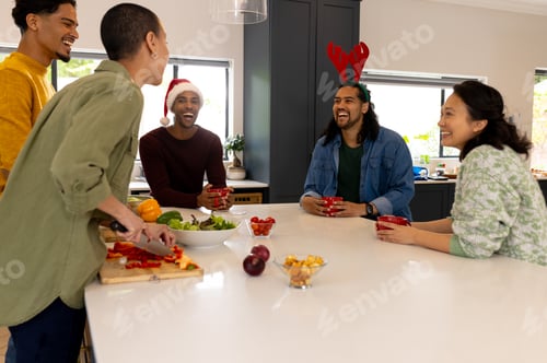 Preview: Christmas time, multiracial friends laughing and preparing holiday meal together at home