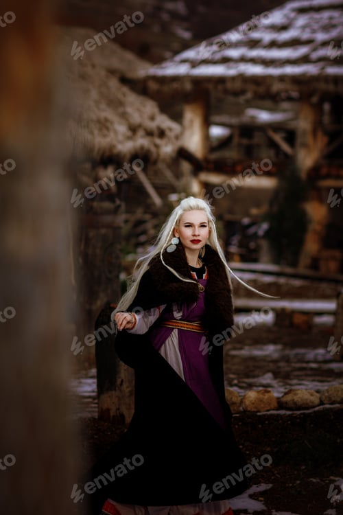 Preview: Beautiful blonde Viking dressed in a black cloak against the backdrop of the castle