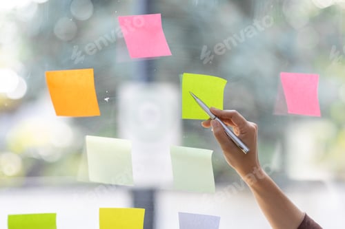 Preview: young indian girl asian woman entrepreneur of small company putting a adhesive sticky notes in glass