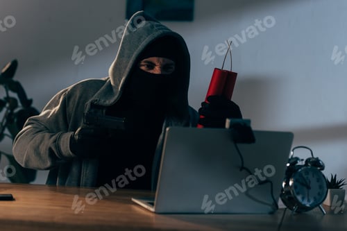 Preview: Aggressive terrorist in mask aiming gun at webcam in dark room