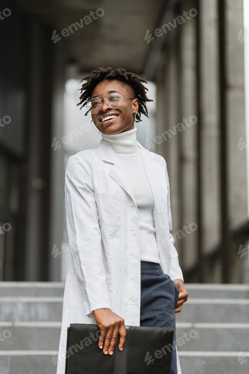 Preview: Smiling Woman in Lab Coat Stands on Steps