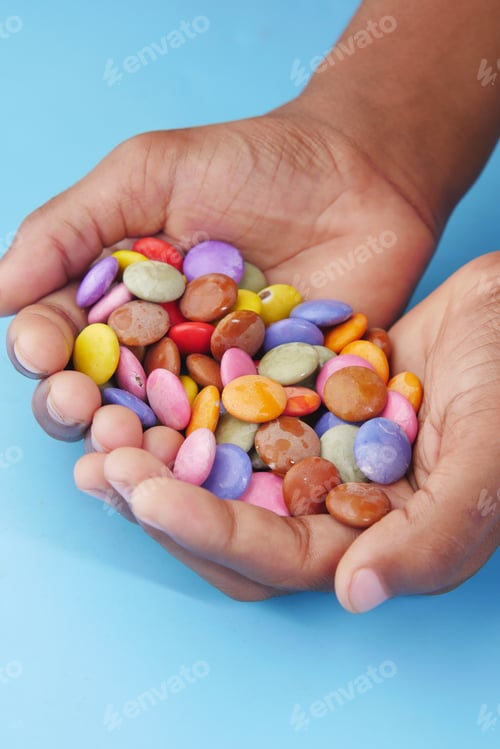 Preview: child boy picking multi-colored sweet candies in a bowl close up