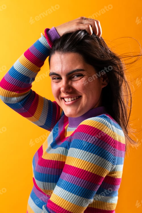 Preview: Young woman smiling and touching hair on yellow background