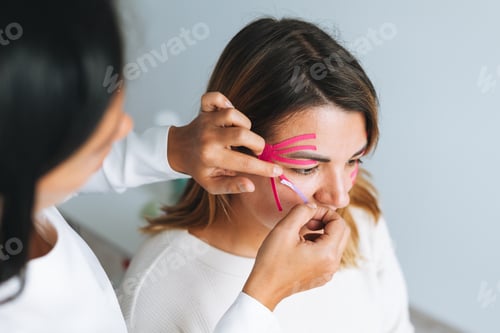 Preview: Doctor cosmetologist makes face taping for patient in cosmetologic clinic