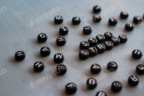 Preview: Alphabet beads with text STAY STRONG on concrete floor.