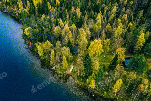 Preview: Aerial view of cottage in autumn colors forest by the blue lake in rural Finland