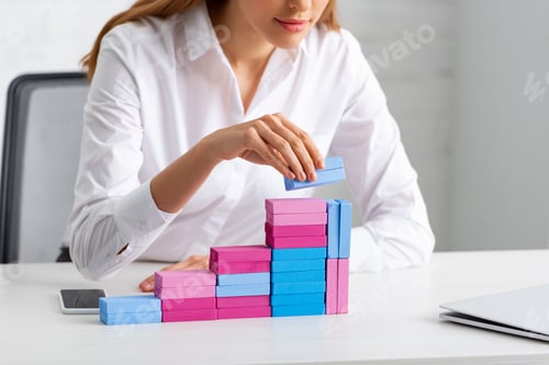 Preview: Cropped view of businesswoman stacking marketing pyramid from building blocks on table in office