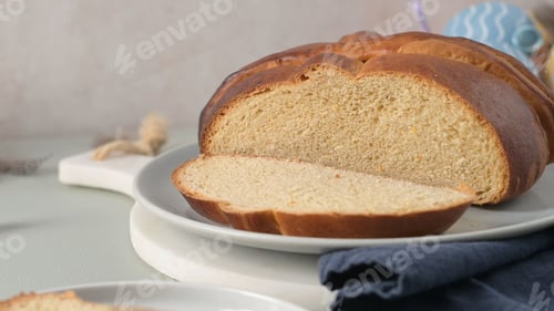 Preview: Sliced traditional Portuguese folar on a white plate with a blue napkin