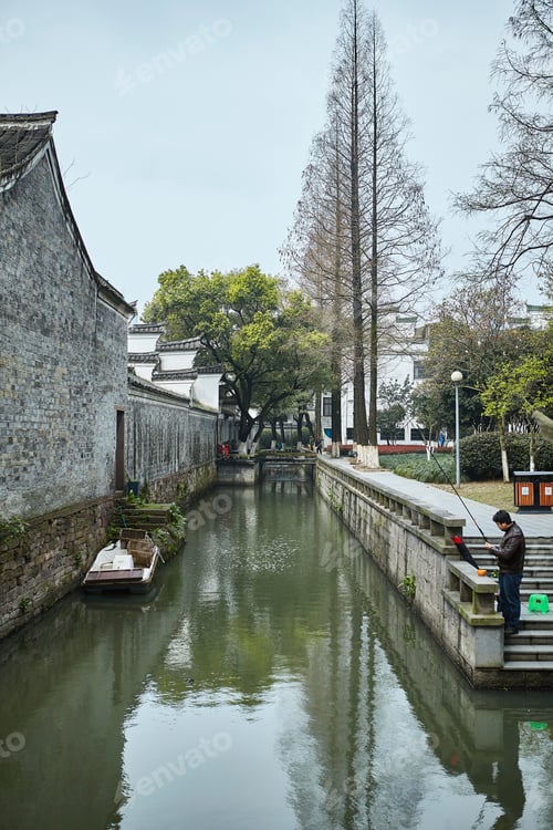 Preview: Tranquil canal with traditional architecture and lush trees