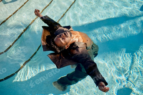 Preview: Man floating peacefully in a clear blue swimming pool, with sunlight reflecting through the water.