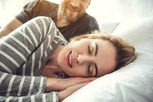 Preview: Portrait Of Tranquil Smiling Woman Sleeping On White Pillow. Caring Partner Is Lying Behind And