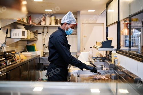 Preview: Close-up of professional latin chef man wearing a protective mask and uniform while working