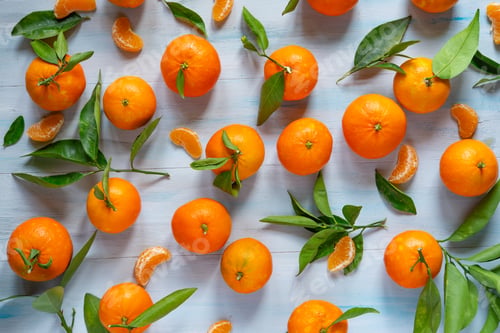 Preview: Fresh tangerines with leaves in a wooden crate on a blue table