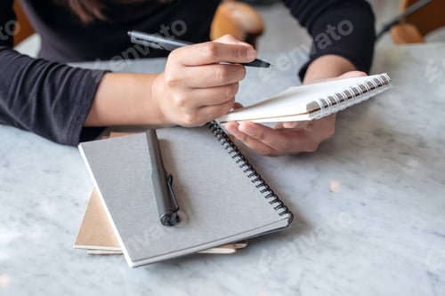 Preview: A woman holding and writing on notebook on the table
