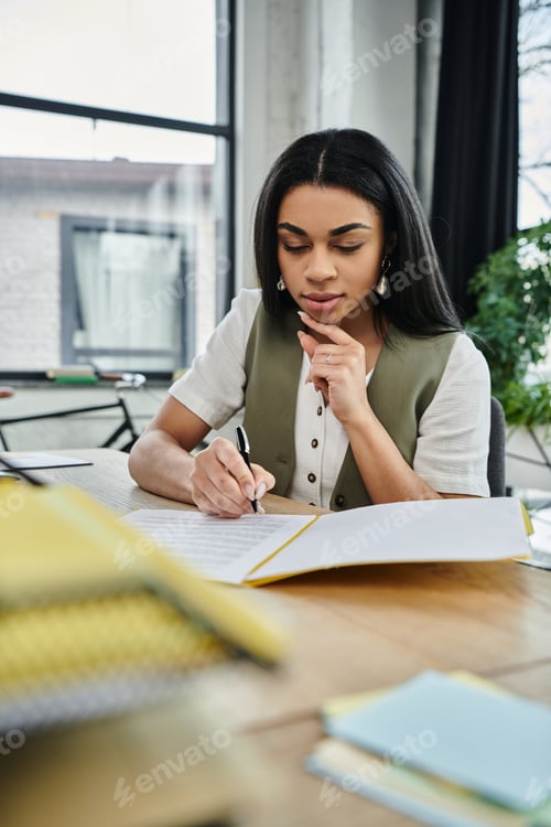 Preview: Thoughtful African American Woman Writing in a Modern Workspace During Daylight Hours
