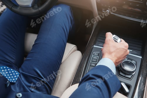 Preview: I love my car. Cropped image of businessman in full suit shifting the gear stick while driving his