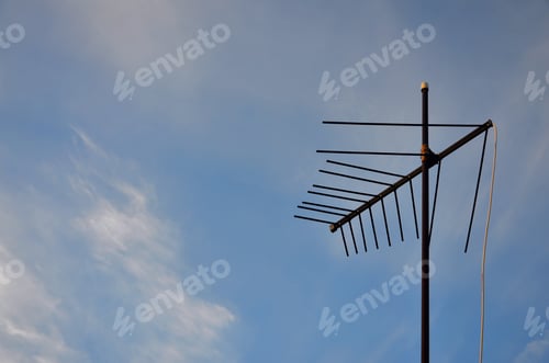 Preview: An old and rusty television antenna against a cloudy blue sky