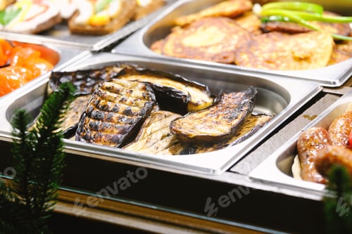 Preview: Delicious warm buffet dishes served in metal trays with grilled eggplant, crispy fritters.