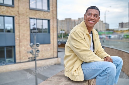 Preview: Young male photographer sitting on the brick wall