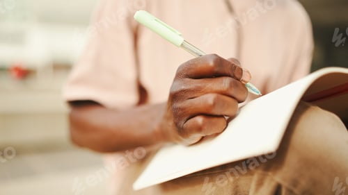 Preview: Close-up of young african student's hand taking notes