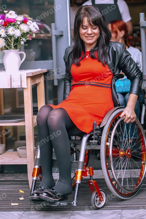 Preview: A happy girl in a wheelchair leaves the caf . Optimistic woman with special needs turns the wheels