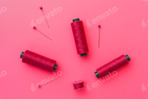 Preview: Pink sewing threads and pins on pink background