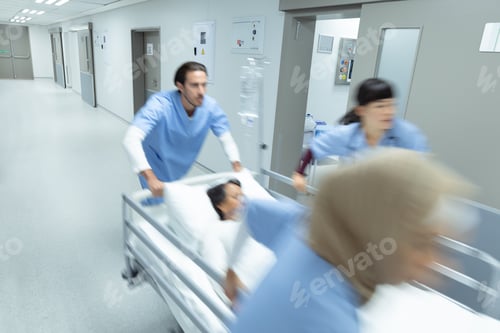 Preview: Side view of diverse medical team pushing emergency stretcher bed in corridor at hospital