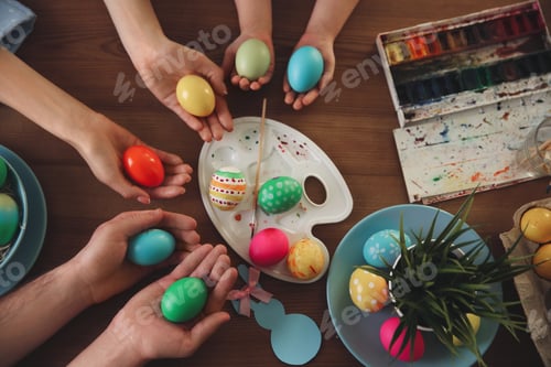 Preview: Father, mother and their child painting Easter eggs at wooden table, top view
