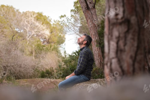 Preview: Man meditating in nature feeling peaceful and tranquil
