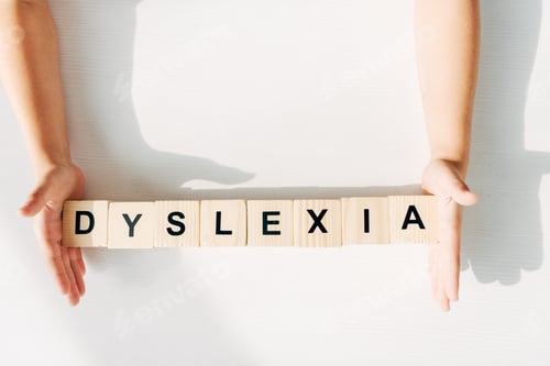 Preview: cropped view of kid with dyslexia holding wooden cubes with lettering